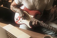 Cool tattooed man playing a guitar in a studio