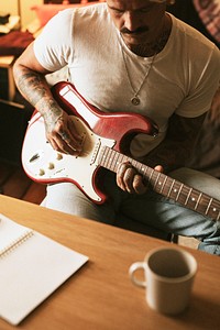 Cool tattooed man playing a guitar in a studio