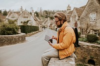 Man taking notes on his tablet village in Cotswolds, UK