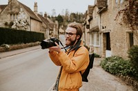 Photographer man taking photos in the village in Cotswolds, UK