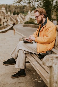 Man sitting on a bench and working on tablet in the village