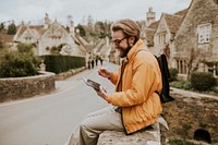 Happy man taking notes on his tablet in Cotswolds village, UK
