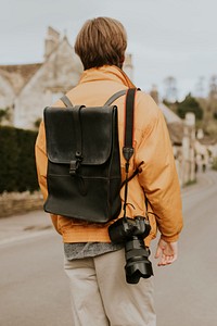 DSLR camera with strap hanging on photographer&rsquo;s shoulder