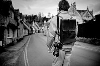 DSLR camera with strap hanging on photographer&rsquo;s shoulder in greyscale