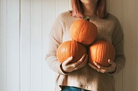 Woman holding Halloween pumpkins in a farmhouse