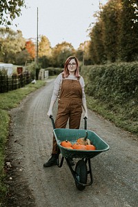 Woman with Halloween pumpkin wheelbarrow dark autumn mood