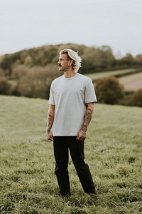 Attractive man in gray t-shirt with design space standing in countryside