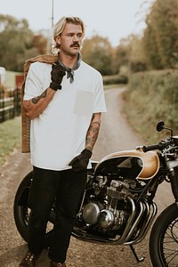 Tattooed biker standing by his vintage motorcycle