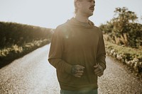 Man in stretchy hoodie jogging in the countryside at sunset