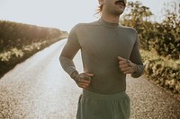 Man in stretch shirt running in the countryside at sunset