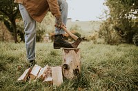 Country man splitting wood with axe on the field