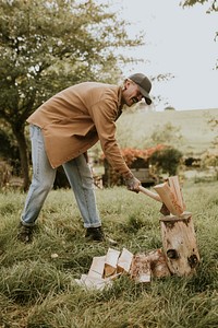 Country man splitting wood with axe on the field