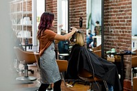 Hairstylist giving a haircut to a customer at a beauty salon 