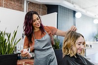 Hairstylist spraying a mouse on her customer's hair 