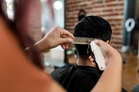 Hairdresser trimming hair of the customer at a barbershop 