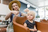 Hairstylist giving a haircut to an adorable blond kid 