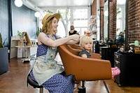 Hairstylist giving a haircut to an adorable blond kid 