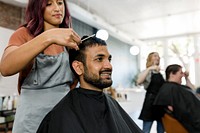 Man getting a haircut from a hair stylist at a barber shop 