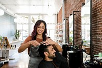 Barber trimming a customer&#39;s hair at a barber shop