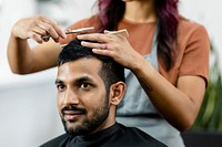 Man getting a haircut from a hair stylist at a barber shop 