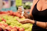 Woman using hand sanitizer, grocery shopping image