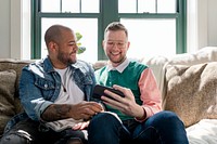 Gay couple taking selfies, sitting on a couch at home