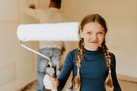 Playful girl helping parent to home paint
