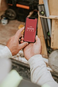 Man holding smartphone mockup psd near a construction site