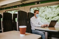 Man wearing mask using laptop on a train in the new normal