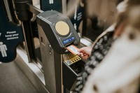 Person inserting a ticket into a train station turnstile