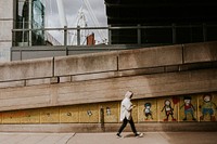 Woman walking past a street art mural graffiti by UK artist Stik at South Bank, Waterloo, London, United Kingdom taken on 22 June 2021