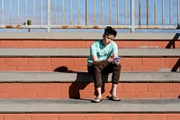 Asian teen boy, listening to music and using a smartphone