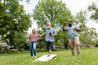 Friends playing cornhole at a summer party in the park