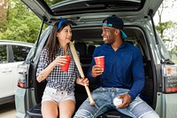 Baseball fans sitting in car boot at a tailgate party