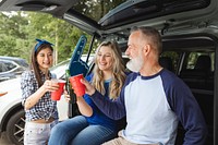 Friends sitting and drinking in the car boot at a tailgate party