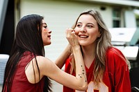 Woman getting her cheeks painted with her team colors