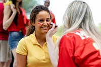 Woman getting her cheeks painted with her team colors