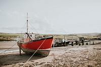 Sailboat stranded on a beach during ebb, Wales, UK