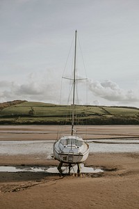 Sailboat stranded on a beach during ebb, Wales, UK