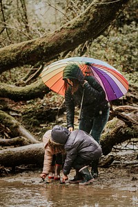 Mother watching her daughters play in the forest on a rainy day