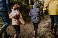 Mother walking with her daughters in the forest rear view