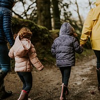 Mother walking with her daughters in the forest rear view