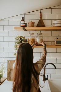 Woman tidying up kitchen wall pantry
