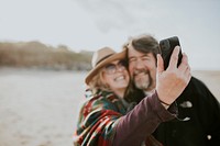 Retired couple on a trip take a selfie by the beach