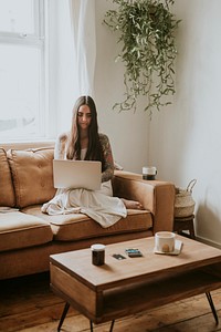 Tattooed woman work from home on a couch