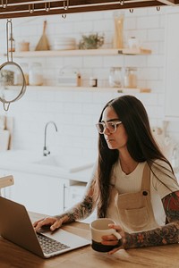 Tattooed woman work from home in her kitchen