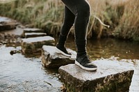 Woman enjoying outdoors adventure crossing the stream 