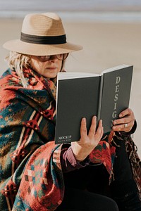 Book psd mockup held by a retired senior by the beach