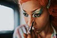 Man in drag applying eyeshadow, entertainment makeup look