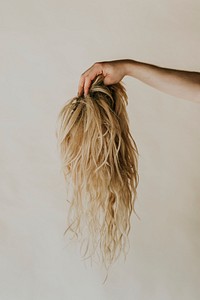 Hand holding blond wig, for cancer patient